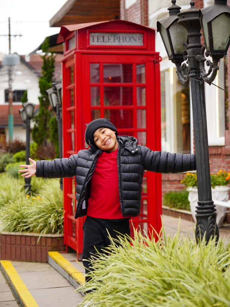 Menino na frente do telefone europeu do centro de gramado